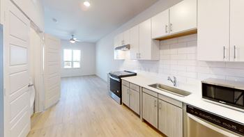 Galley kitchen with white cabinetry and stainless appliances